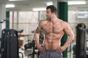 Hairy Healthy Young Man Standing Strong In The Gym And Flexing Muscles - Muscular Athletic Bodybuilder Fitness Model Posing After Exercises
