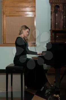 Beautiful Thoughtful Girl Sitting Near Piano - Fashion Studio Portrait