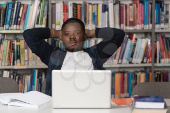 Stressed African Student Of High School Sitting At The Library Desk - Shallow Depth Of Field
