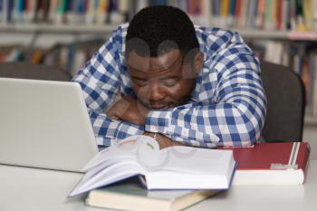 Sleeping African Student Sitting And Leaning On Pile Of Books In College - Shallow Depth Of Field