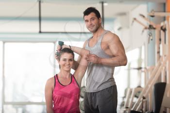 Personal Trainer Showing Young Woman How To Train Triceps Exercise With Dumbbell In A Gym