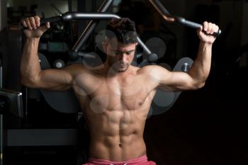 Muscular Man Doing Heavy Weight Exercise For Back On Machine