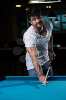 Young Man Playing Billiards Lined Up To Shoot Easy Winning Shot
