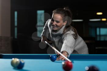 Young Woman Lining To Hit Ball On Pool Table