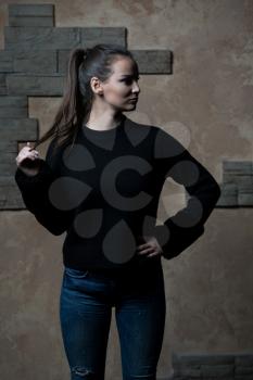 Portrait of Pretty Woman Dressed in Fashionable Clothes Standing Against Wall Background With Area for Advertising Content Copy Space
