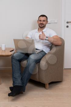Confident Businessman at Home He Is Having a Coffee Break in the Living Room and Networking With His Laptop