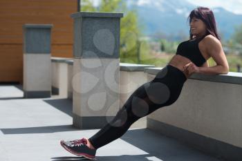 Attractive Woman Resting On Concrete Outdoors After Exercise In Fitness Center