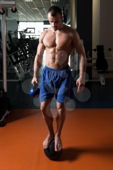 Athlete Doing Kettle Bell Exercise On Medicine Ball As Part Of Bodybuilding Training In Gym