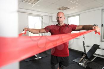 Athlete in Sport Sportswear Workout With Elastic Resistance Band - Doing Shoulder Or Back Exercises in Gym