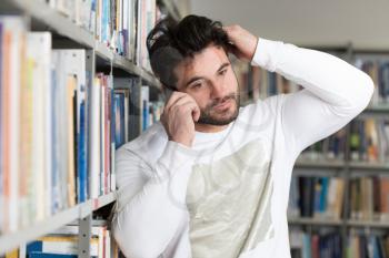 Portrait of a Happy Handsome Man Talking on Mobile Phone in Library at the University