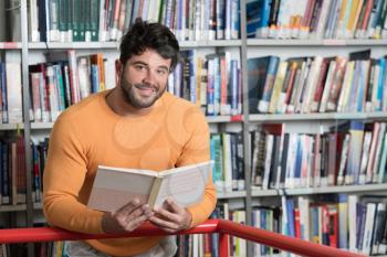 Handsome Male Student With Books Working in a High School Library