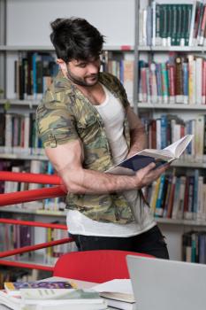 Handsome Muscular Man With Dark Hair Standing in the Library - Bodybuilder Preparing Exam and Learning Lessons in School Library