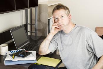 Mature man preparing to do income taxes with computer, calculator, booklet and coffee on desk