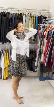 Full vertical portrait of mature Asian woman in walk-in closet putting on her scarf