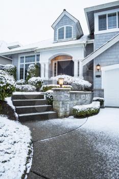 Vertical photo of side walk leading to suburban home with snow on ground