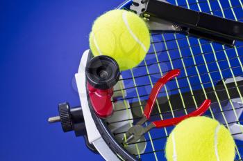 Tennis racket in stringing machine being repaired on blue background