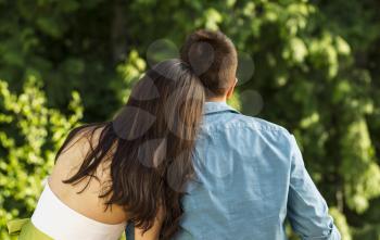Horizontal photo of a young adult couple holding each other while looking into the woods