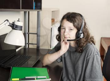 Young girl taking a break from homework  with headset on while sitting at her desk