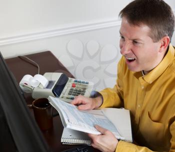 Photo of mature man, looking at data on computer monitor, working on taxes while going into a total rage of anger with office equipment in background 
