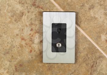 Horizontal photo of a phone jack and cable outlet on tiled wall 