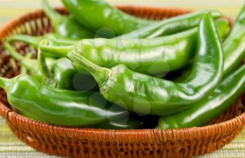 Closeup horizontal photo of fresh Korean Green Peppers in basket with textured table cloth underneath