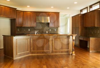 Horizontal photo of a new residential kitchen with stone counter tops, cherry cabinets and hardwood floors 