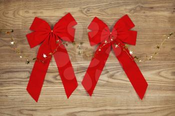 Overhead view of Christmas red bows and golden stars on string   positioned on rustic wooden boards.  
