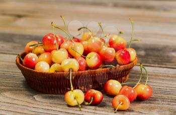 Closeup horizontal front view of fresh Rainier cherries in basket on rustic wood