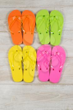 Vertical image of four pairs of new sandals placed on aged wood
