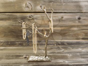 Front view image of natural pearls on chrome metal tree with rustic wood in background 
