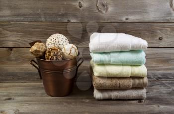 Horizontal photo of clean stacked towels and metal bucket filled with decorations on rustic wood