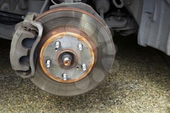 Closeup horizontal photo of exposed car brake drum and brakes inside of wheel well