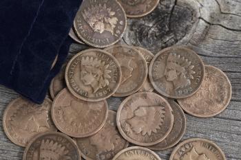 Close up view of United States Vintage pennies spilling out of small bag on rustic wood