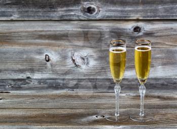 Golden champagne in elegant glasses on rustic wood 