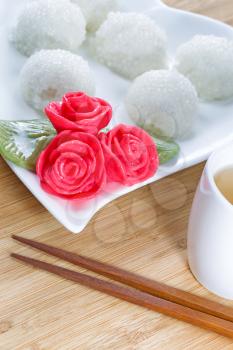 Vertical image of Chinese sweet sticky rice balls, in background, red decoration roses, and green tea with natural bamboo background  