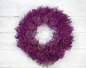 Top view angled shot of seasonal wreath made of lavender on rustic white wood.