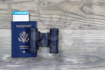 United States passport, boarding pass and binoculars on faded wooden boards. 