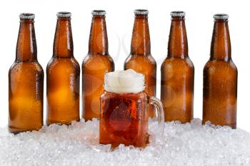 Frosted mug of beer in front of a six pack of bottled beer with drops and ice isolated on white background