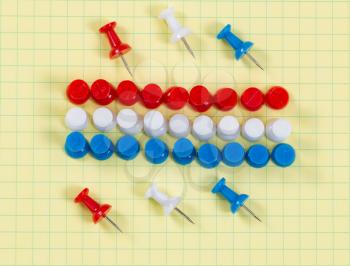 Close up of red, white and blue thumbtacks pinned on yellow graph paper. Patriotic concept for USA colors. 