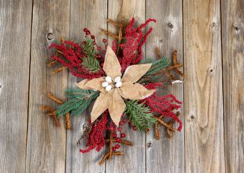 Holiday wreath, cloth flower in center, on rustic wood. Layout in horizontal format. 