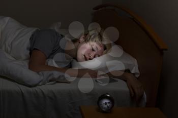 Teenage girl sleeping bed with her cell phone on night stand. Teen surrounded by technology even late at night. 