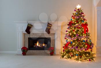 Bright Christmas tree and glowing fireplace in living room. 