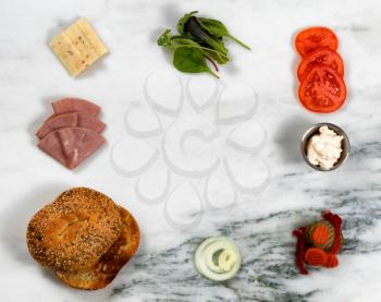Overhead view of sandwich ingredients, forming circle on white marble stone. 

