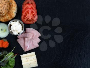 Overhead view of sandwich ingredients, left side for frame, on natural dark slate stone. Plenty of copy space. 