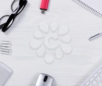 Top view of various office work objects forming circle pattern on white desktop.