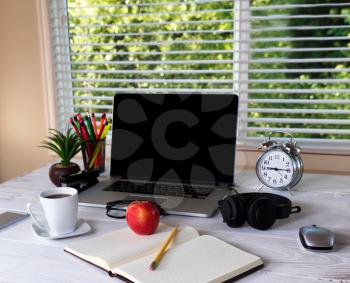 Working desktop in front of large window with bright daylight and trees in background