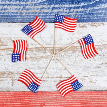 Small USA flags forming pinwheel formation on red, white and blue rustic boards. Fourth of July holiday concept for United States of America.  