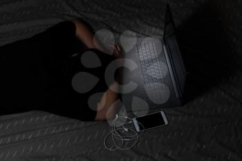 Teen girl falls asleep with her computer still on while in bed. Light effect on computer keyboard. 