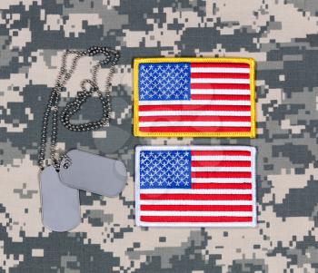 Small USA flag patches and identification tags on military uniform.