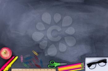 Back to school concept with student supplies on lower part of chalkboard.
